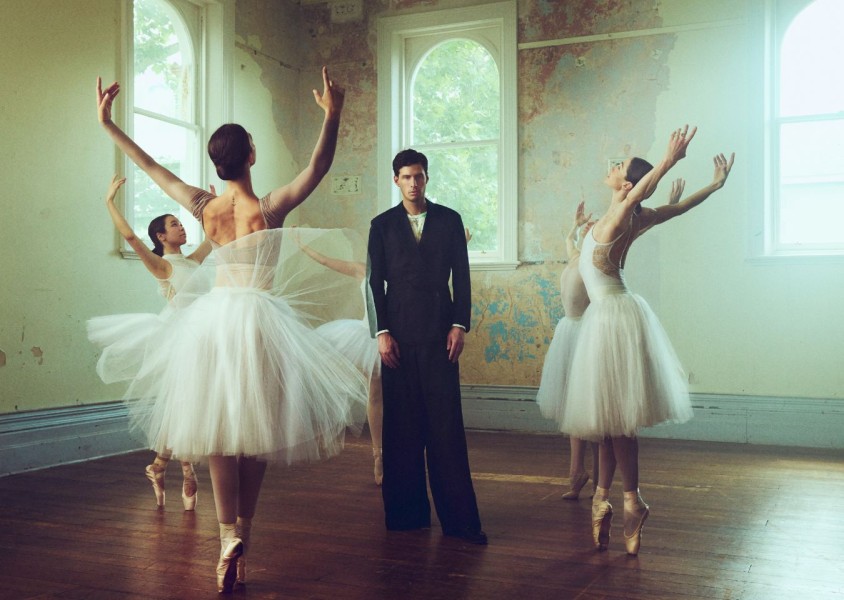 SWIM stood in a black suit surrounded by four ballerinas dancingx